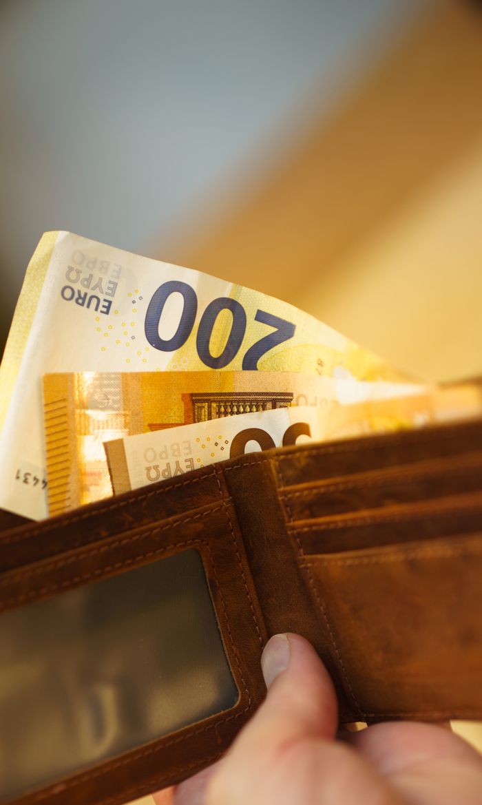 about-us-01 Close-up of a hand holding a leather wallet filled with 200 euro banknotes, highlighting finance and economy.