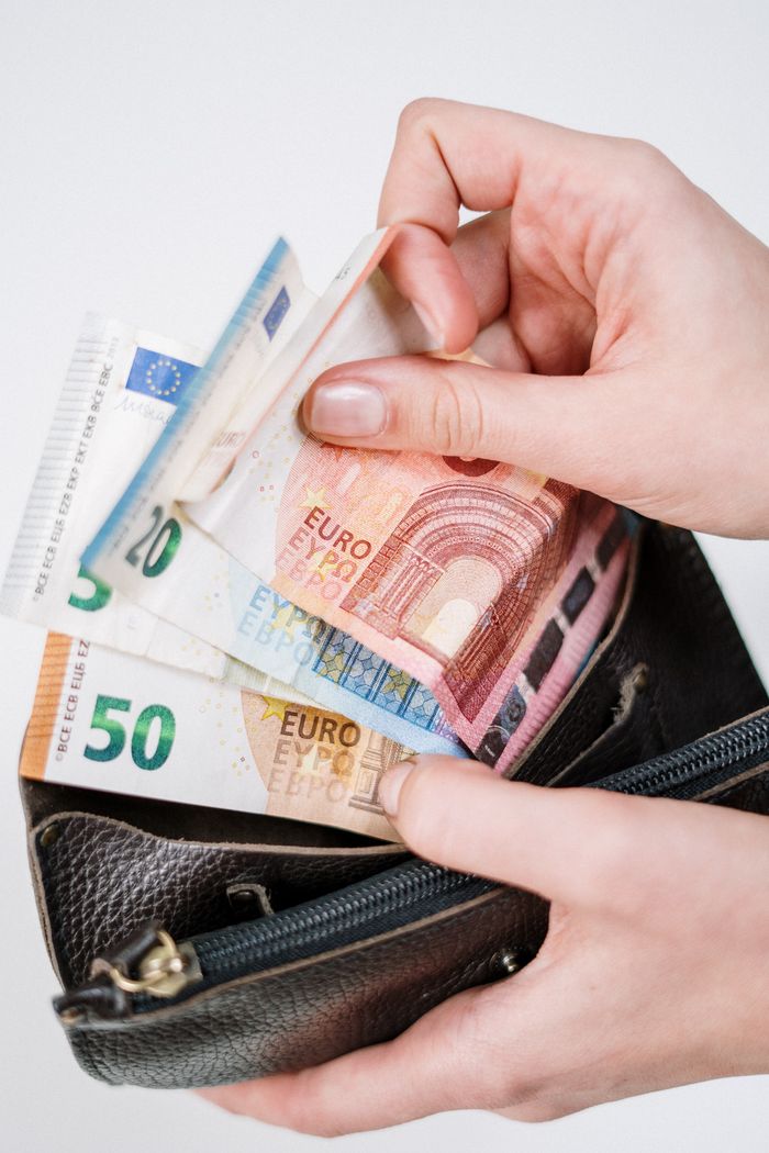 about-us-02 Close-up of hands counting euro banknotes from a leather wallet, representing financial transactions.